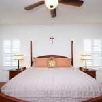 View of bedroom with tall bed posts showing windows with custom shutters