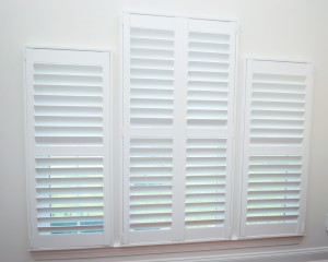 Inside view of 3 side by side windows with custom shutters white walls