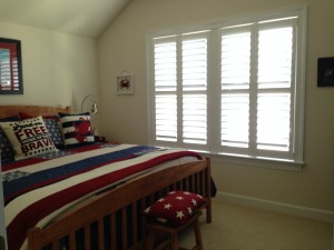 A bedroom with windows that have plantation shutters from A Shade Above Millville DE